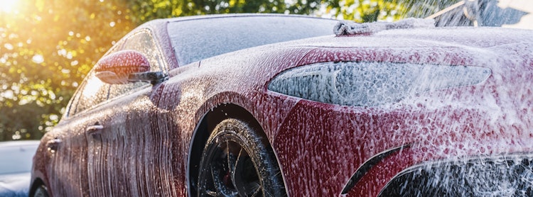 Red sedan being washed by hand