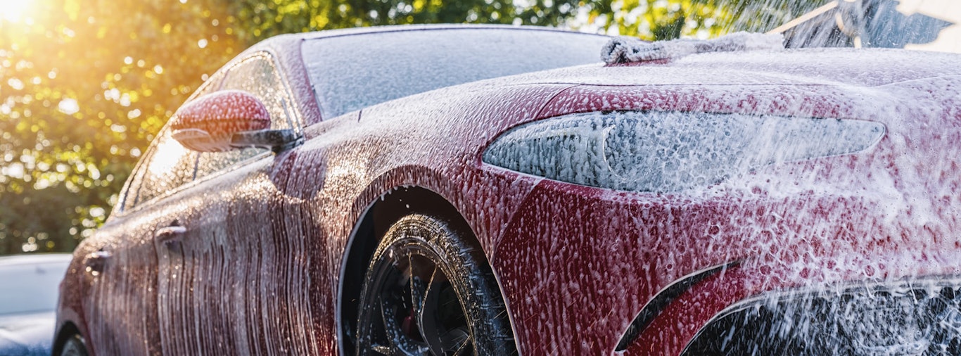 Red sedan being washed by hand