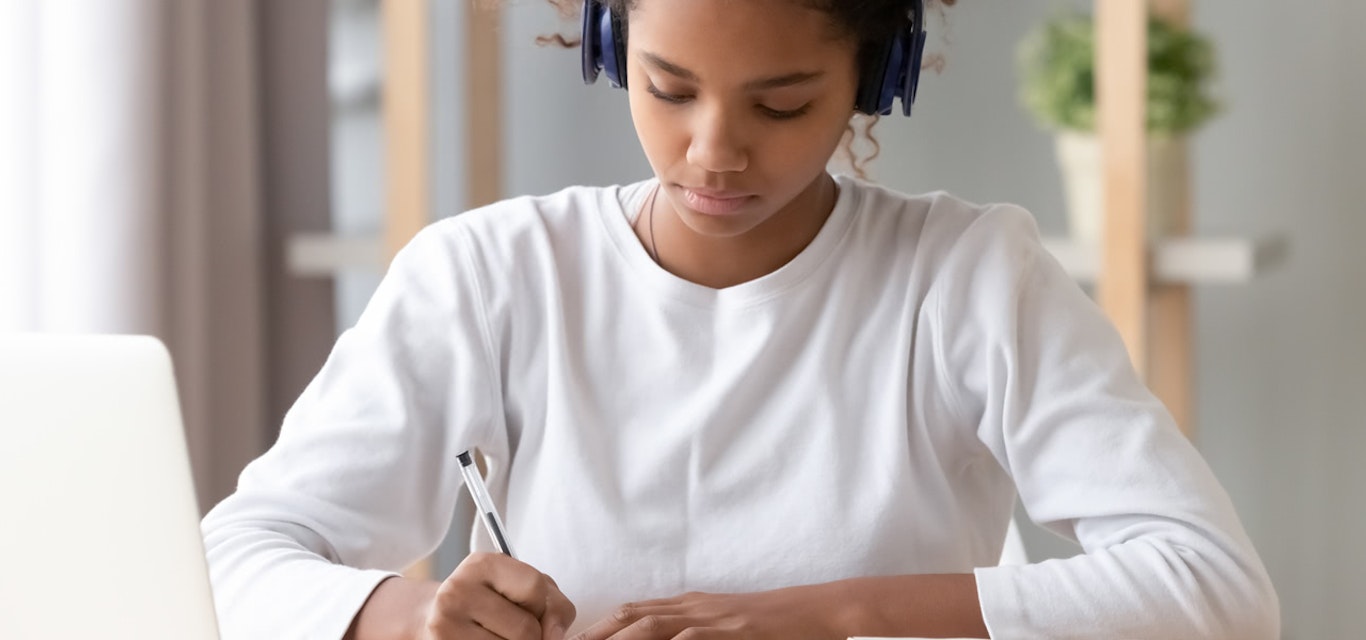 Student writing at a desk.