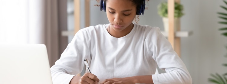 Student writing at a desk.