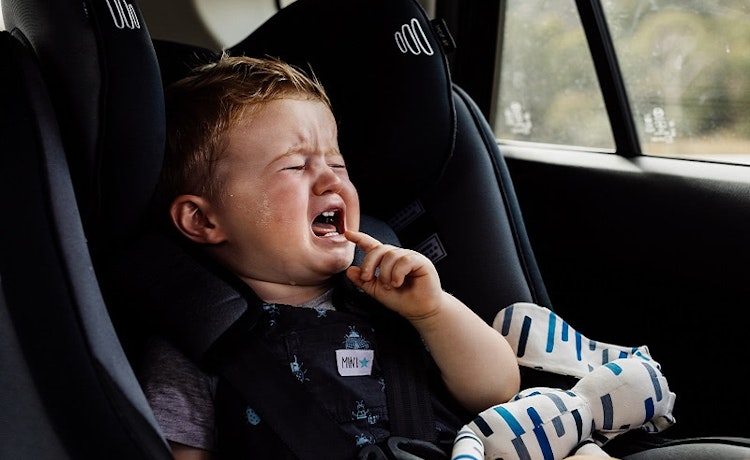 Crying toddler in car seat in a hot car