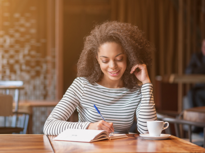 woman sitting in a cafe writing in a notebook