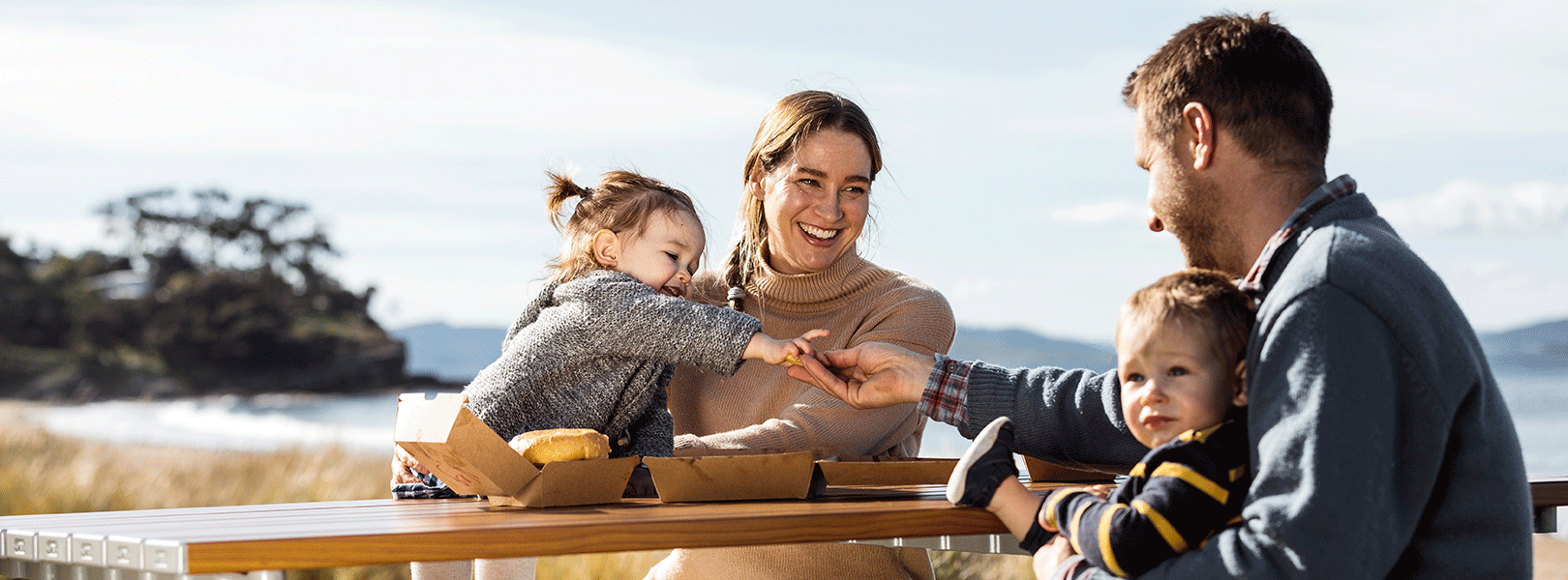 Smiling family eating fast food at beach
