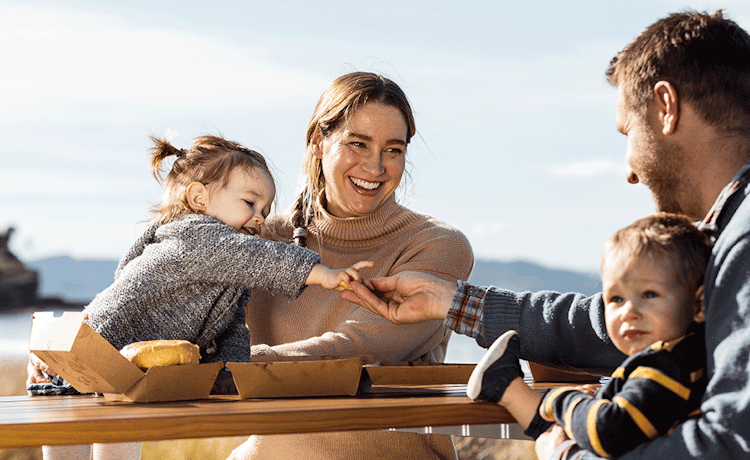 Smiling family eating fast food at beach