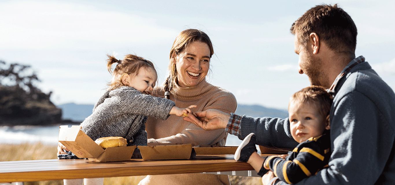 Smiling family eating fast food at beach