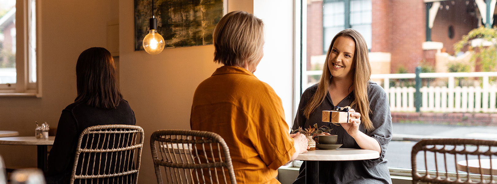 Young lady gives small wrapped gift to her Mother