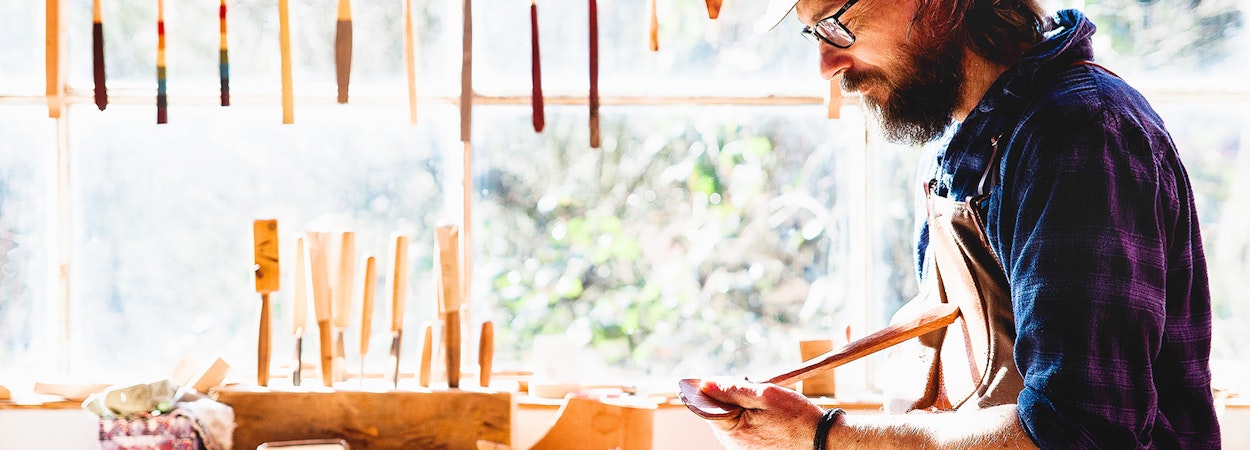 Craftsman oiling his finished wooden spoon