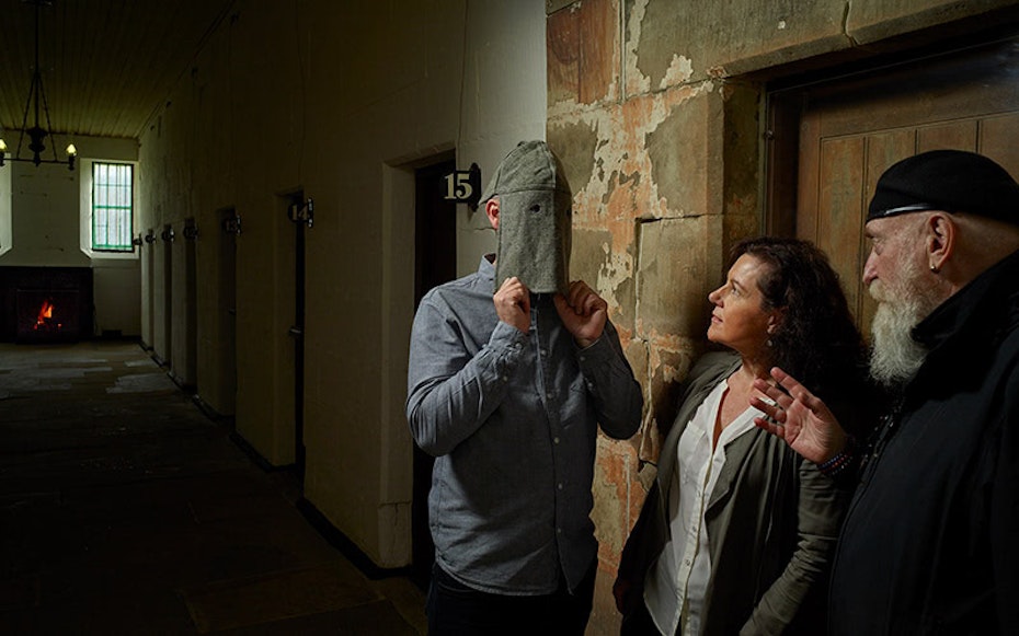 Port Arthur tour guide demonstrating a full-faced hood within the prison