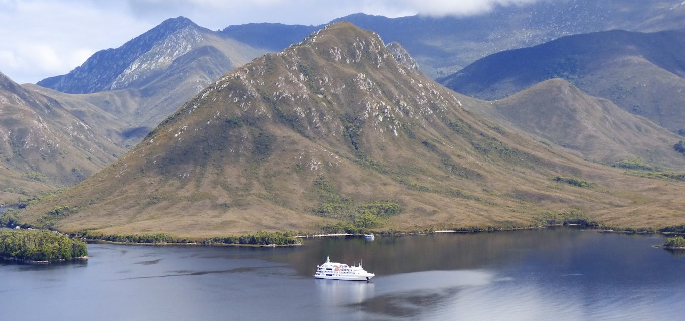Balmoral Hill Small crusie ship off the coast of a mountainous region.
