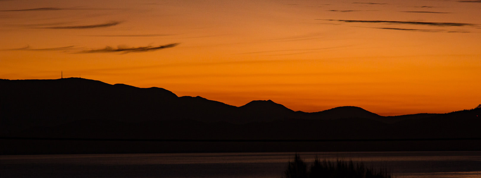 Sillhouette of Mount Wellington and Hobart in front of an orange sky