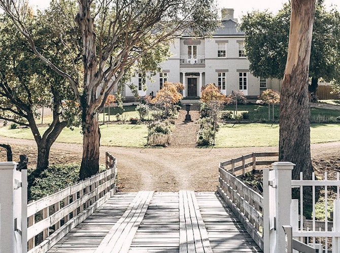 A view of Prospect House through trees and across the entry bridge