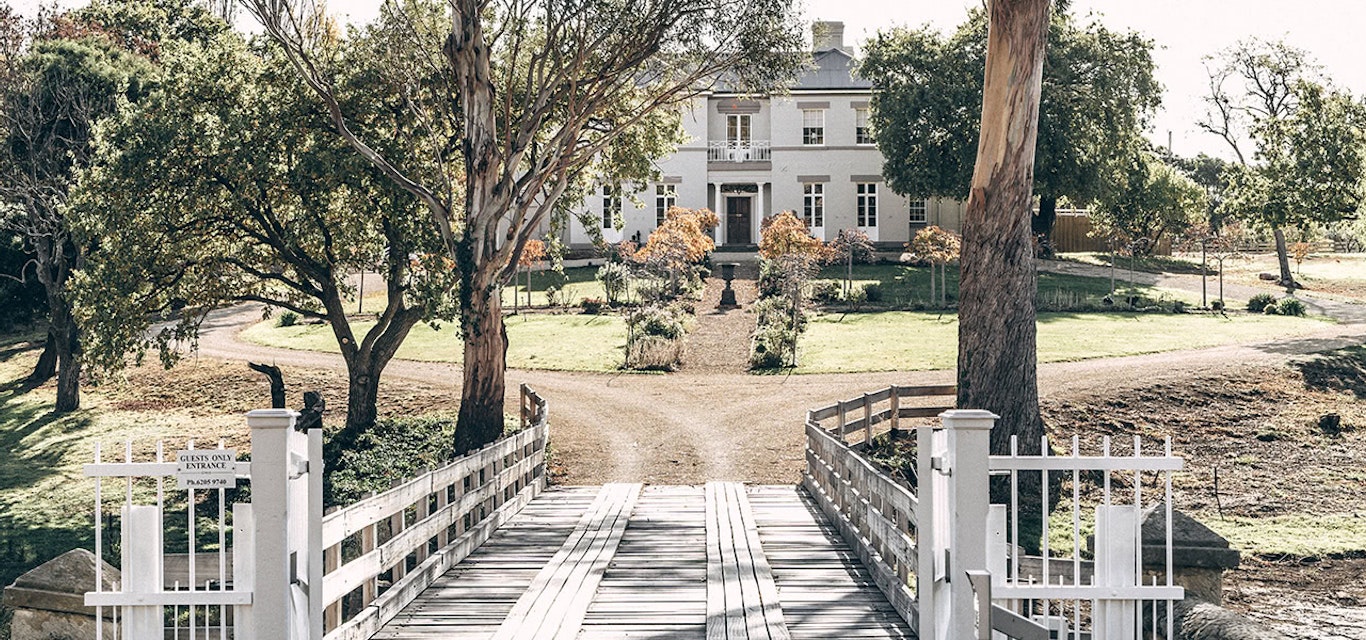 A view of Prospect House through trees and across the entry bridge