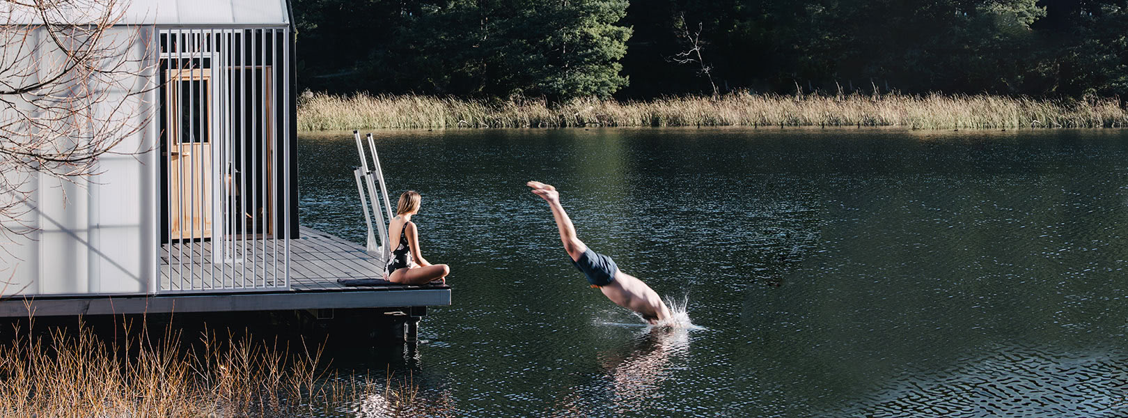 A man dives into a still lake