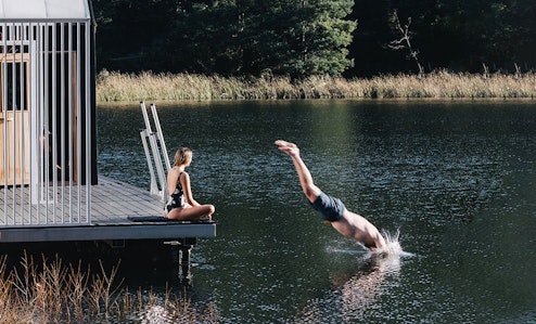 A man dives into a still lake