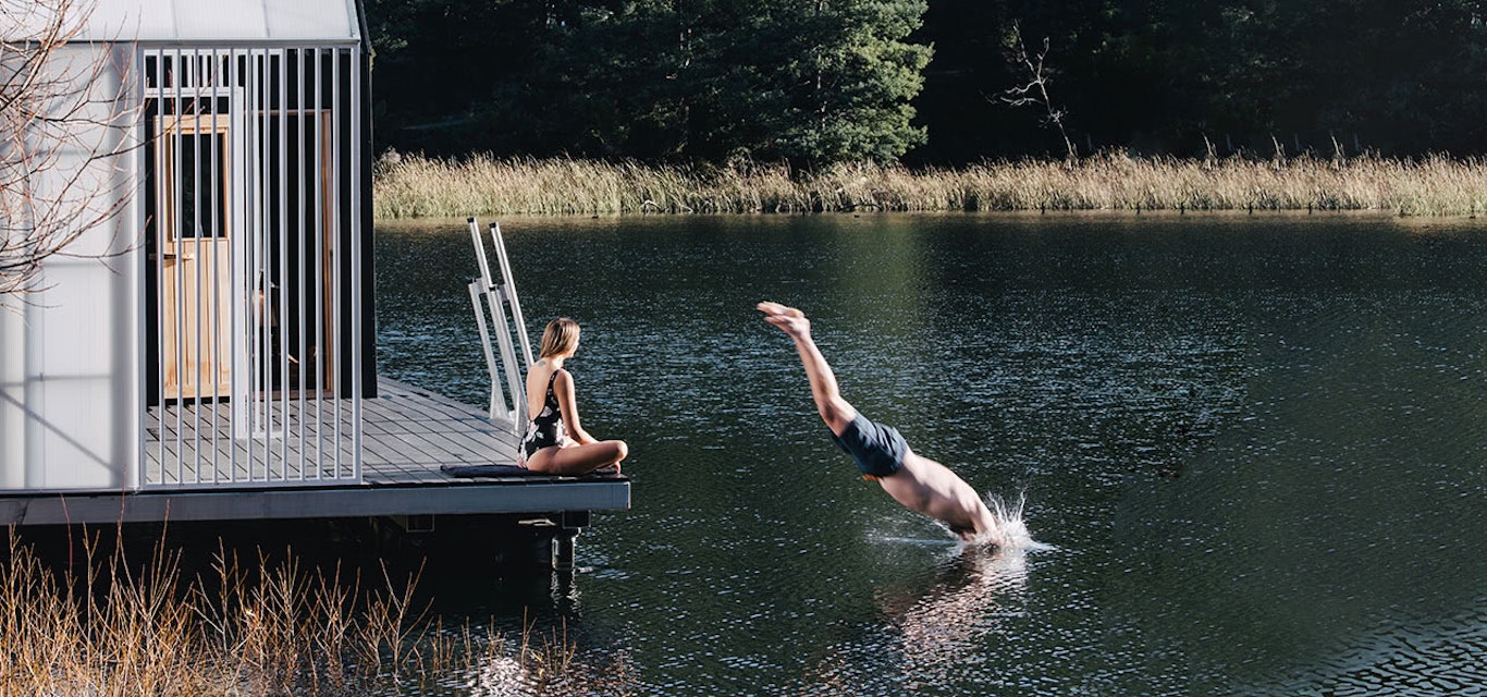 A man dives into a still lake