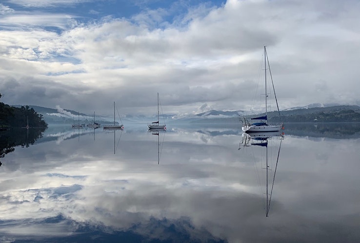 Yachts moored on extremely still water creating perfect reflections