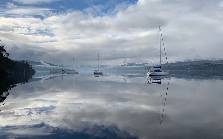 Yachts moored on extremely still water creating perfect reflections