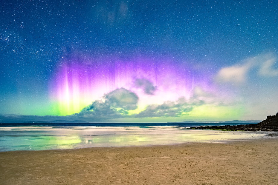 Purple and green aurora australis at the beach