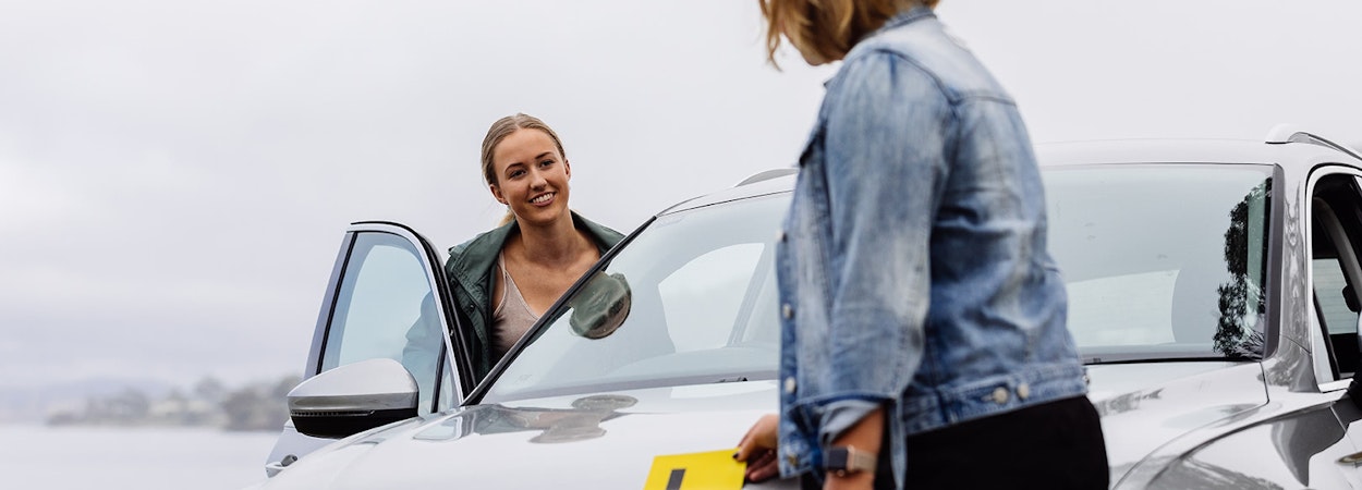 Young learner-driver getting into car with her mother