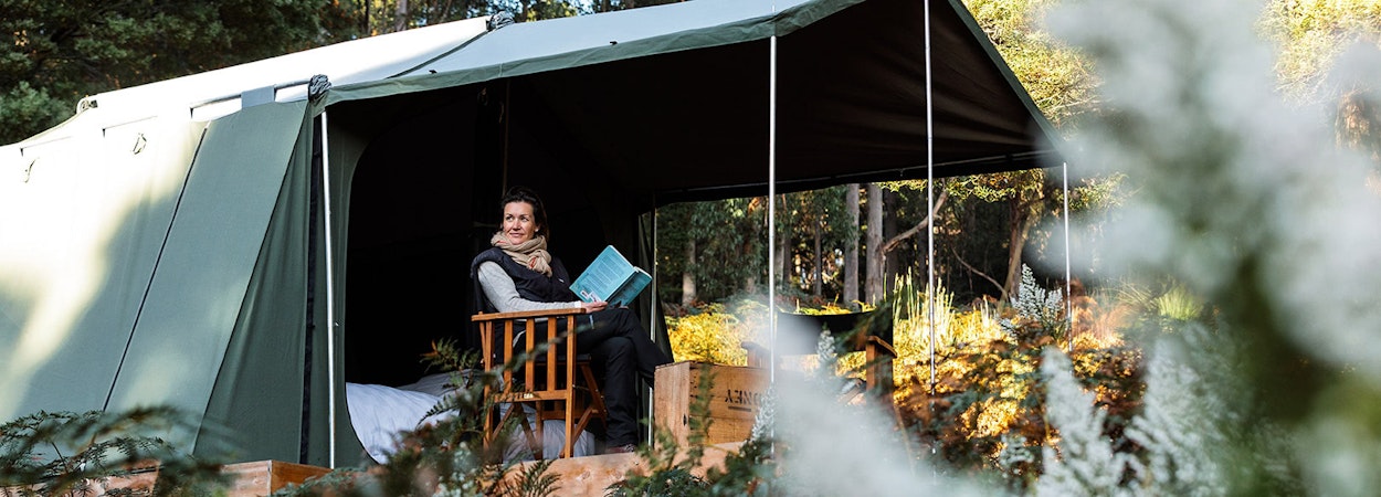 A woman reads a book in a tent on Bruny Island