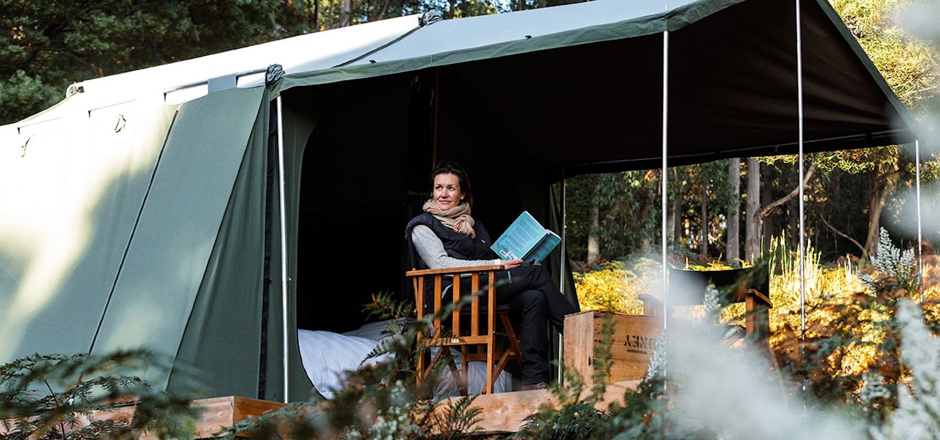 Soaking up the peace and tranquillity. A woman reads a book in a tent on Bruny Island