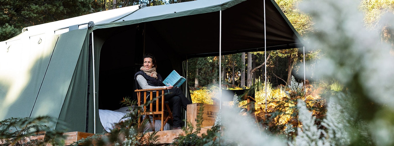 A woman reads a book in a tent on Bruny Island