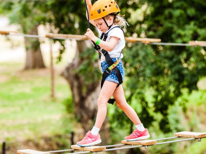 Child walking on a high ropes course bridge