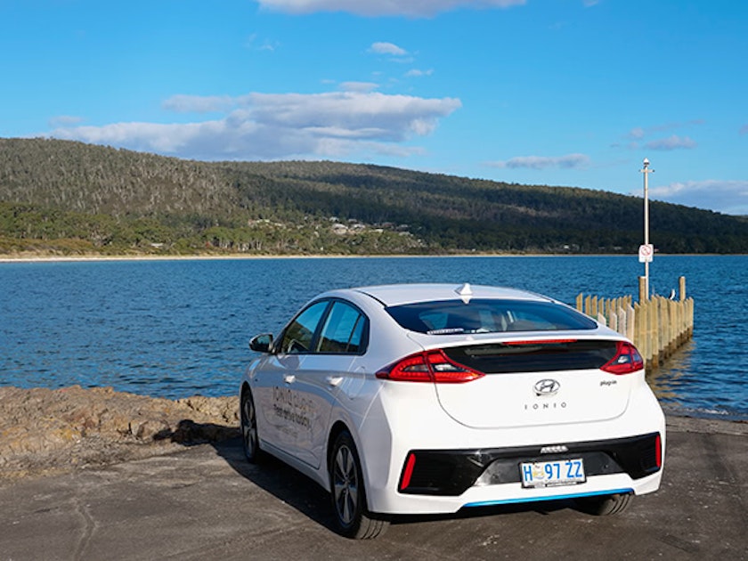 White Hyundai electric vehicle parked next to jetty and water