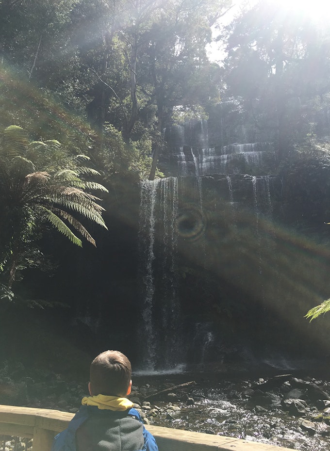 A child in front of a waterfall.