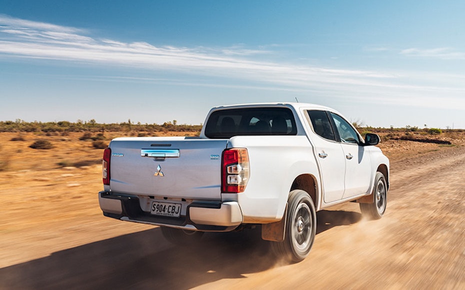 White Mitsubishi Triton driving on dirt road