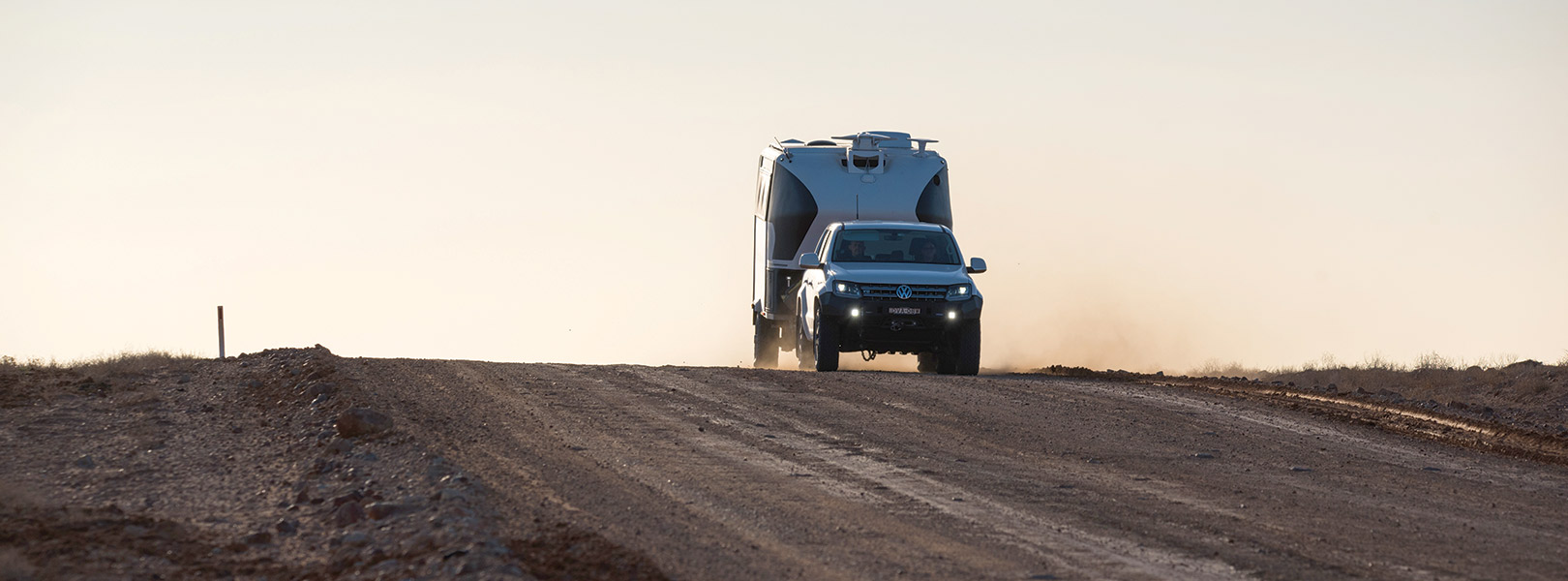 VW pulling a caravan across a remote road
