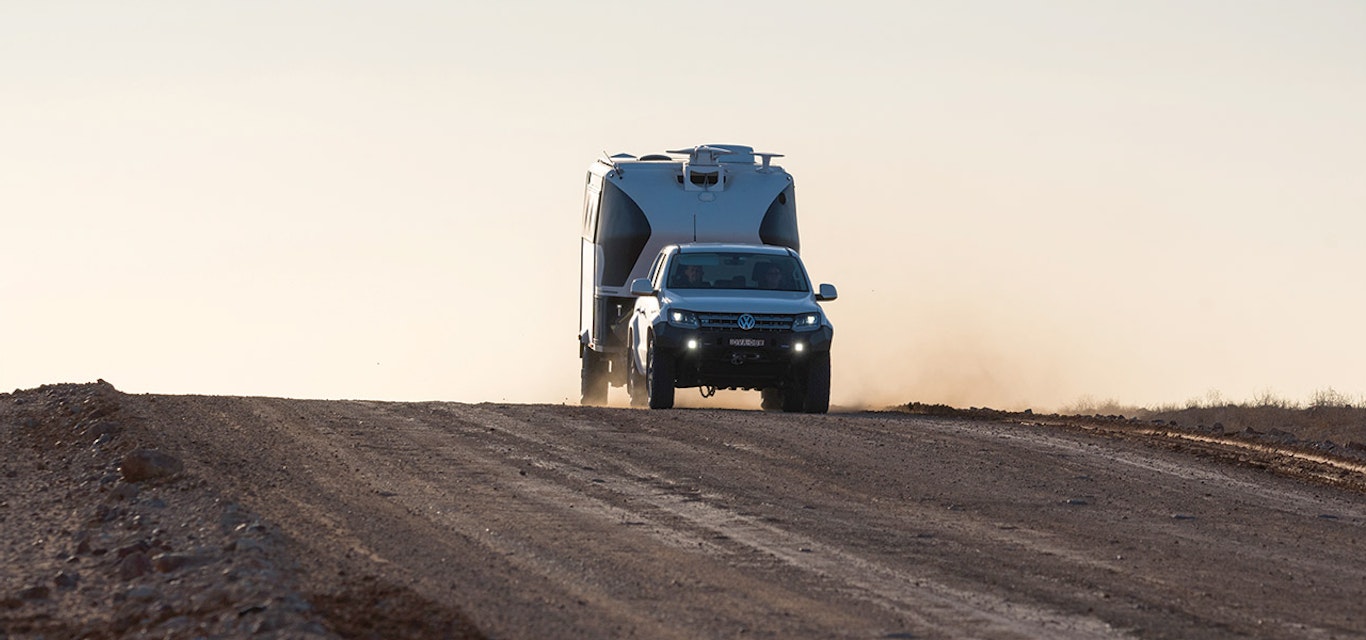 VW pulling a caravan across a remote road