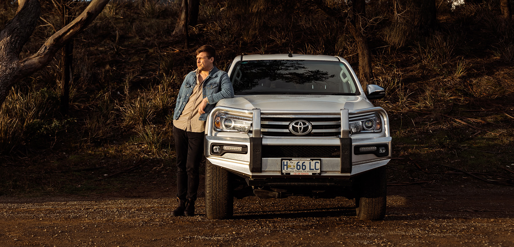 Young driver leaning on a Toyota Ute bonnet in the bush