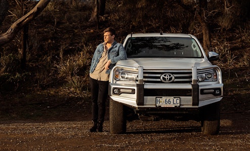 Young driver leaning on a Toyota Ute bonnet in the bush