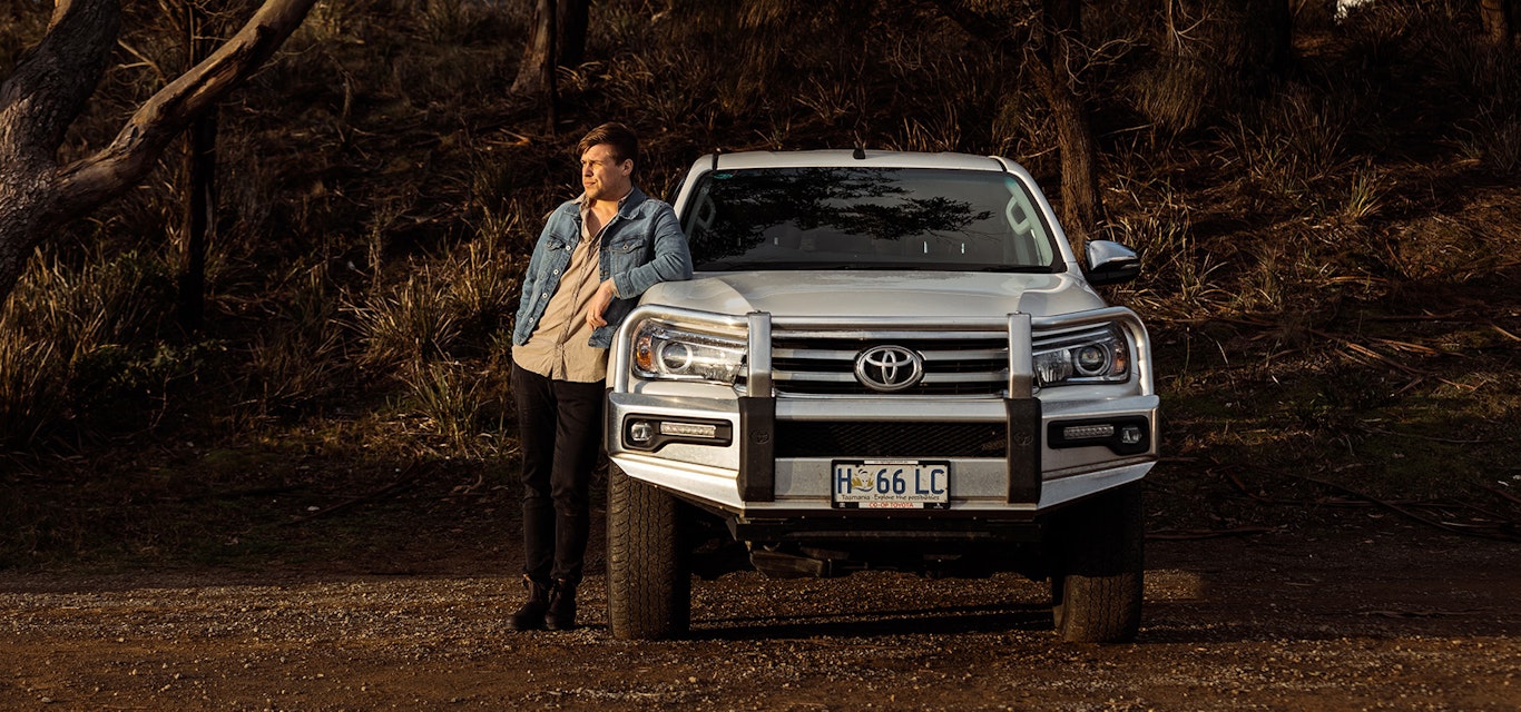 Young driver leaning on a Toyota Ute bonnet in the bush