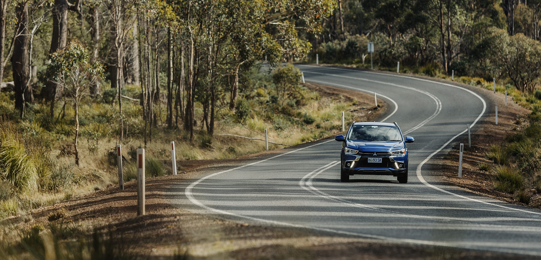 Blue Mitsubishi driving along rural road