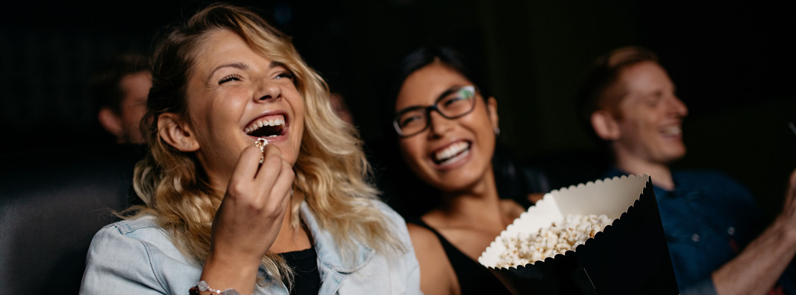 Two women smiling and eating popcorn