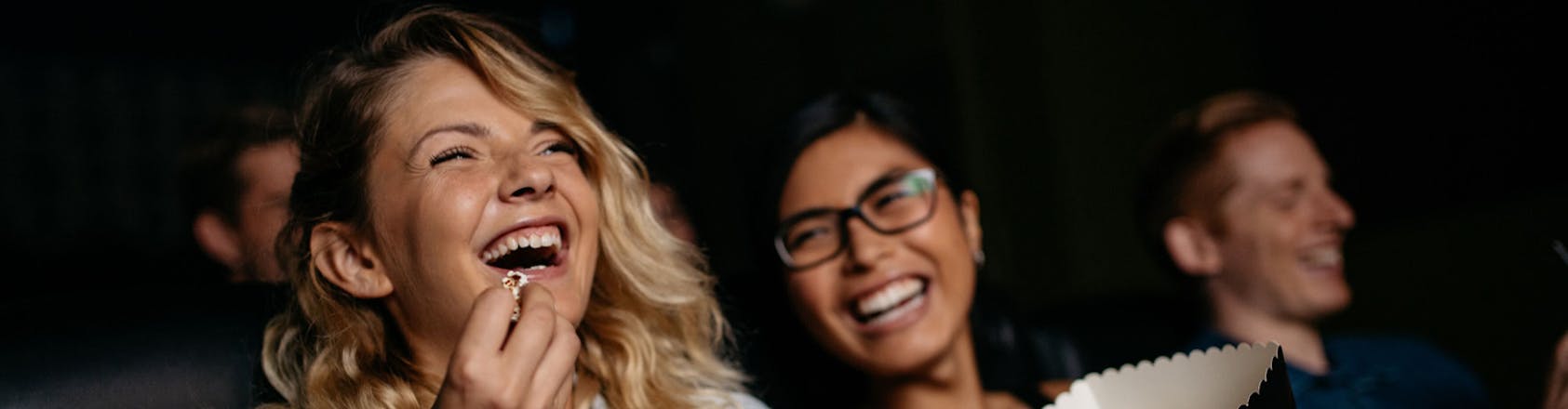 Two women smiling and eating popcorn