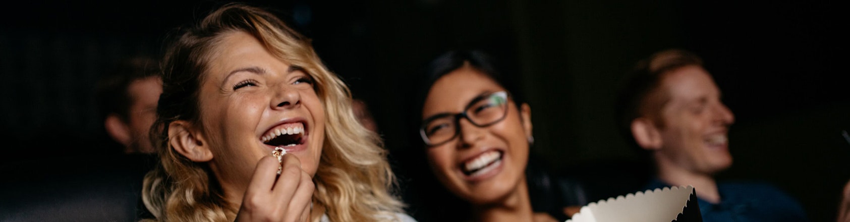 Two women smiling and eating popcorn