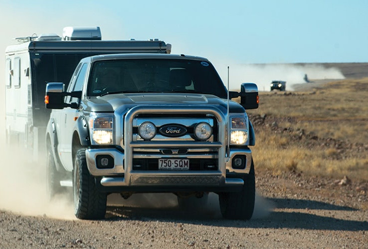 Car driving with caravan attached in the outback.