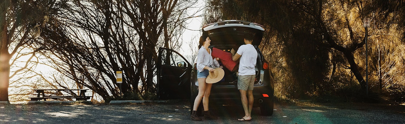 Young couple packing their things into the car boot