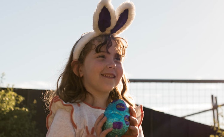Smiling girl holding Easter egg and wearing rabbit ears