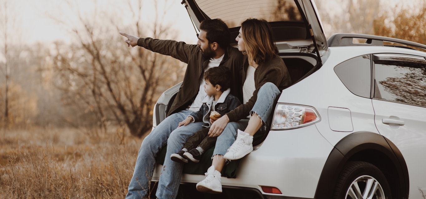 Family looking out to the distance while sitting in car boot