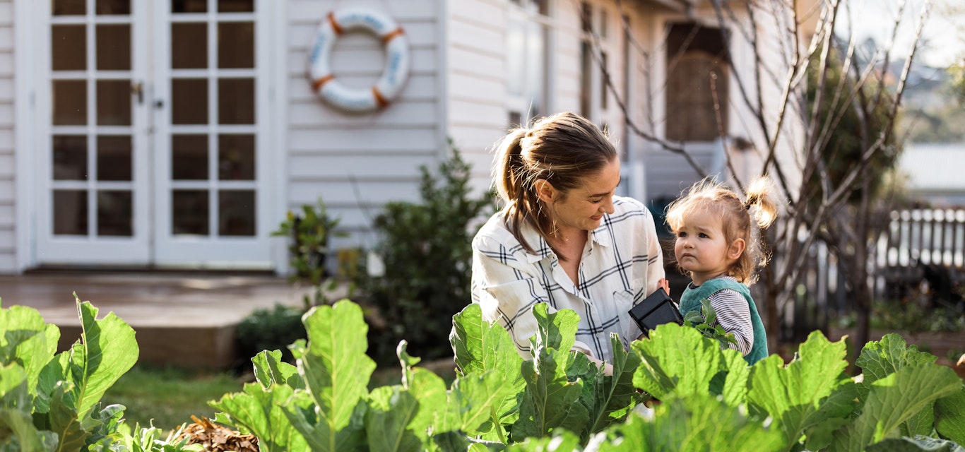 Parent and child smiling in front of vegetable patch