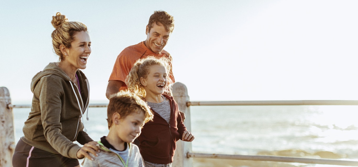 Family running together beside the beach.