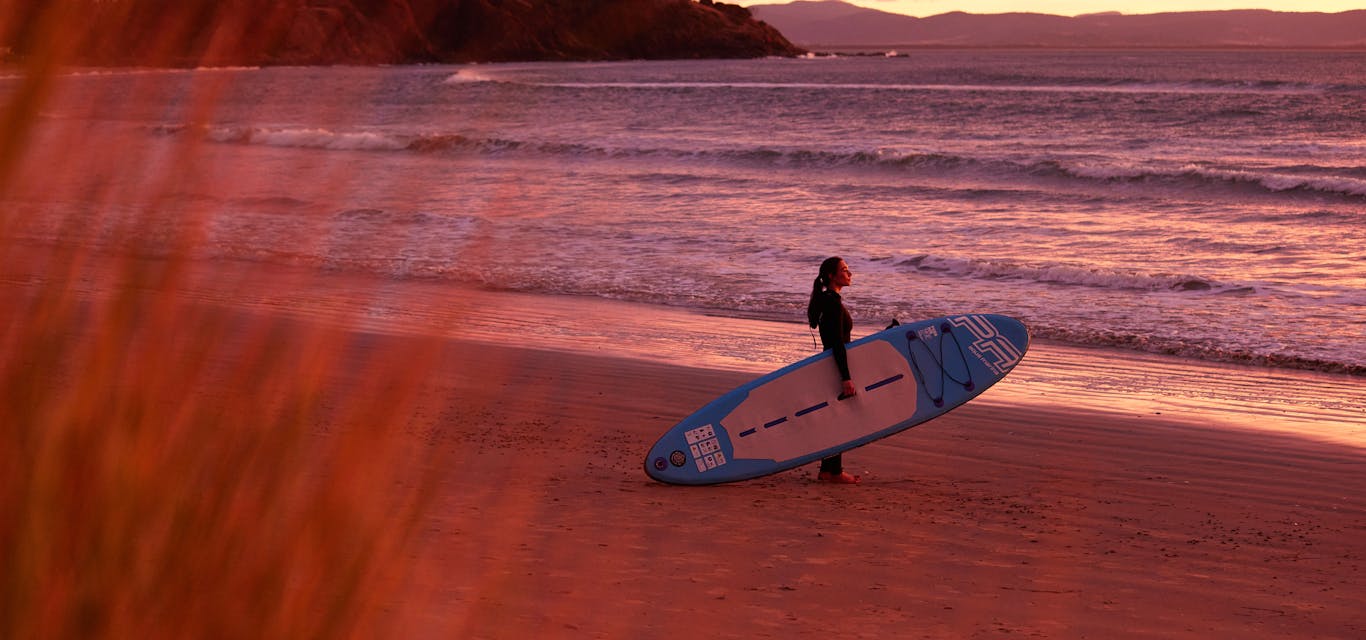 Getting ready to surf at sunrise on the beach.