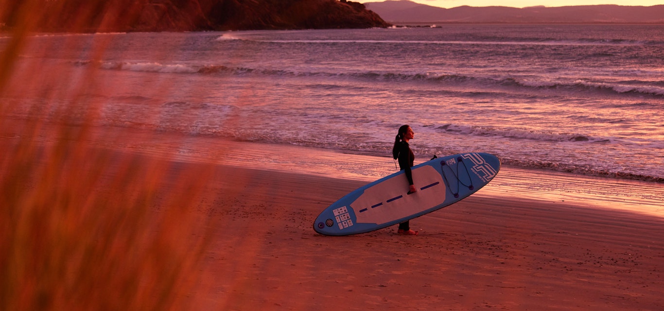 Getting ready to surf at sunrise on the beach.