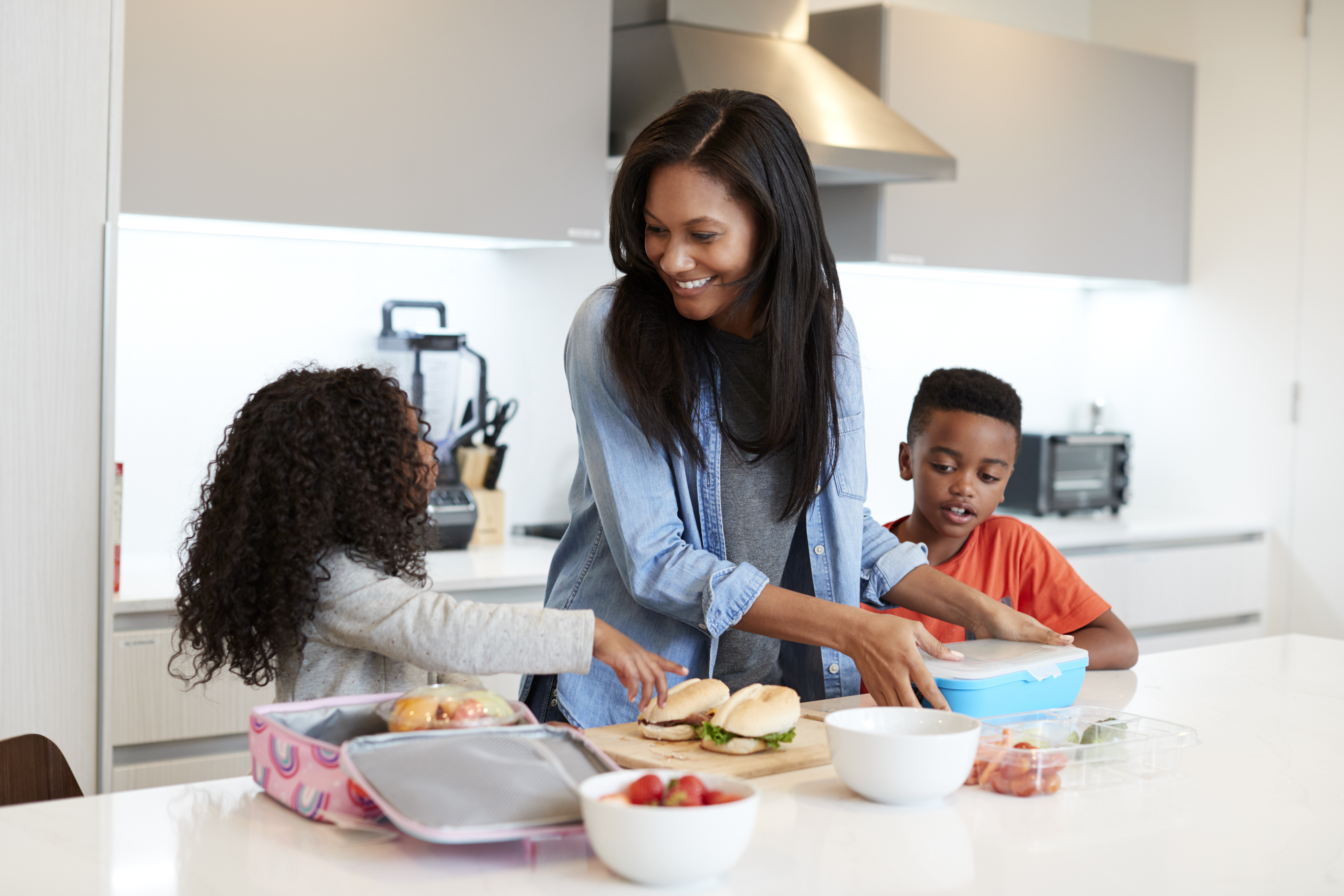 Woman packing lunchboxes with her two children
