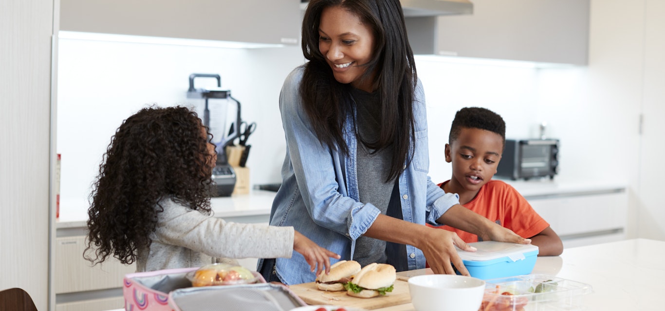 Woman packing lunchboxes with her two children