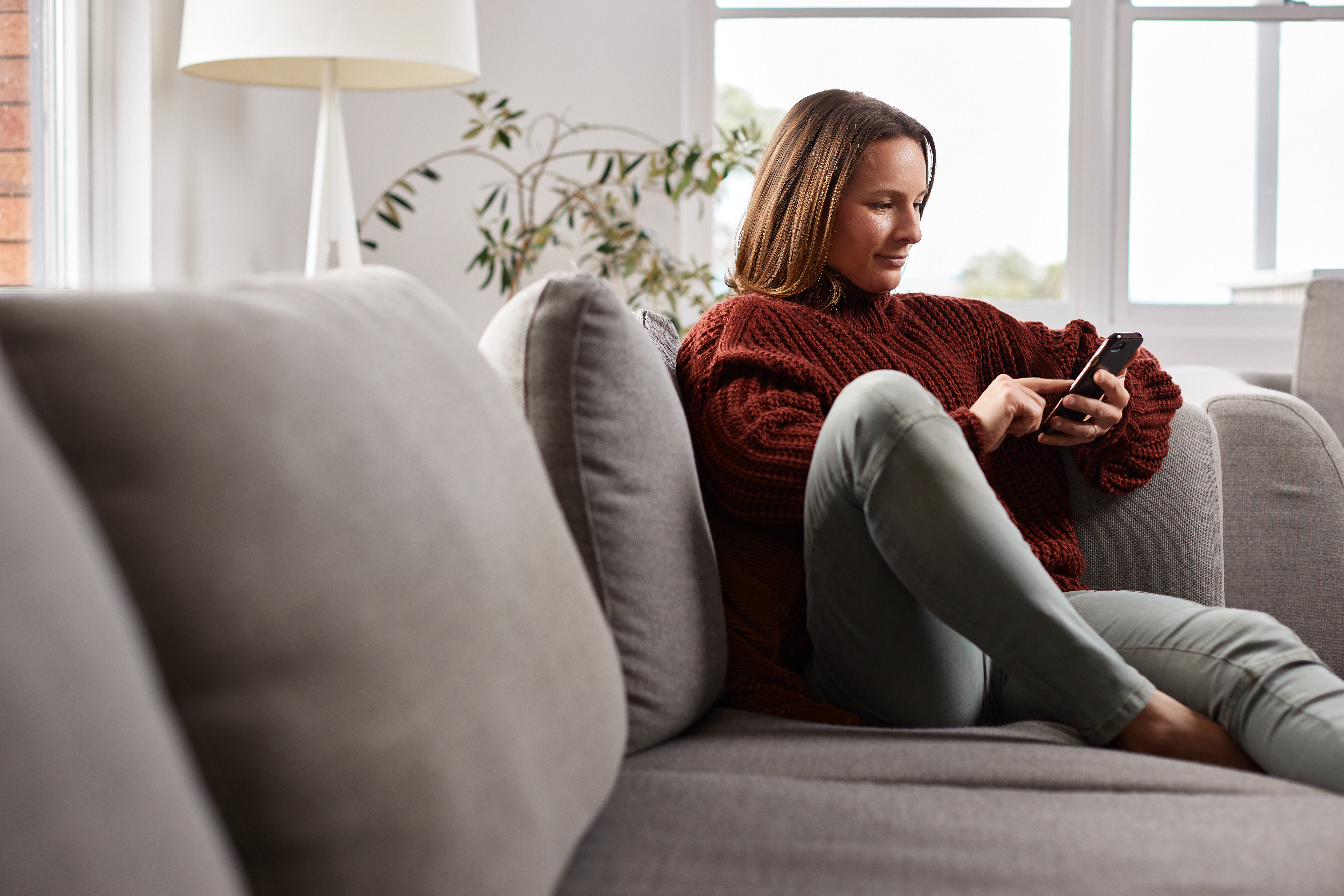 woman at home on couch looking at phone